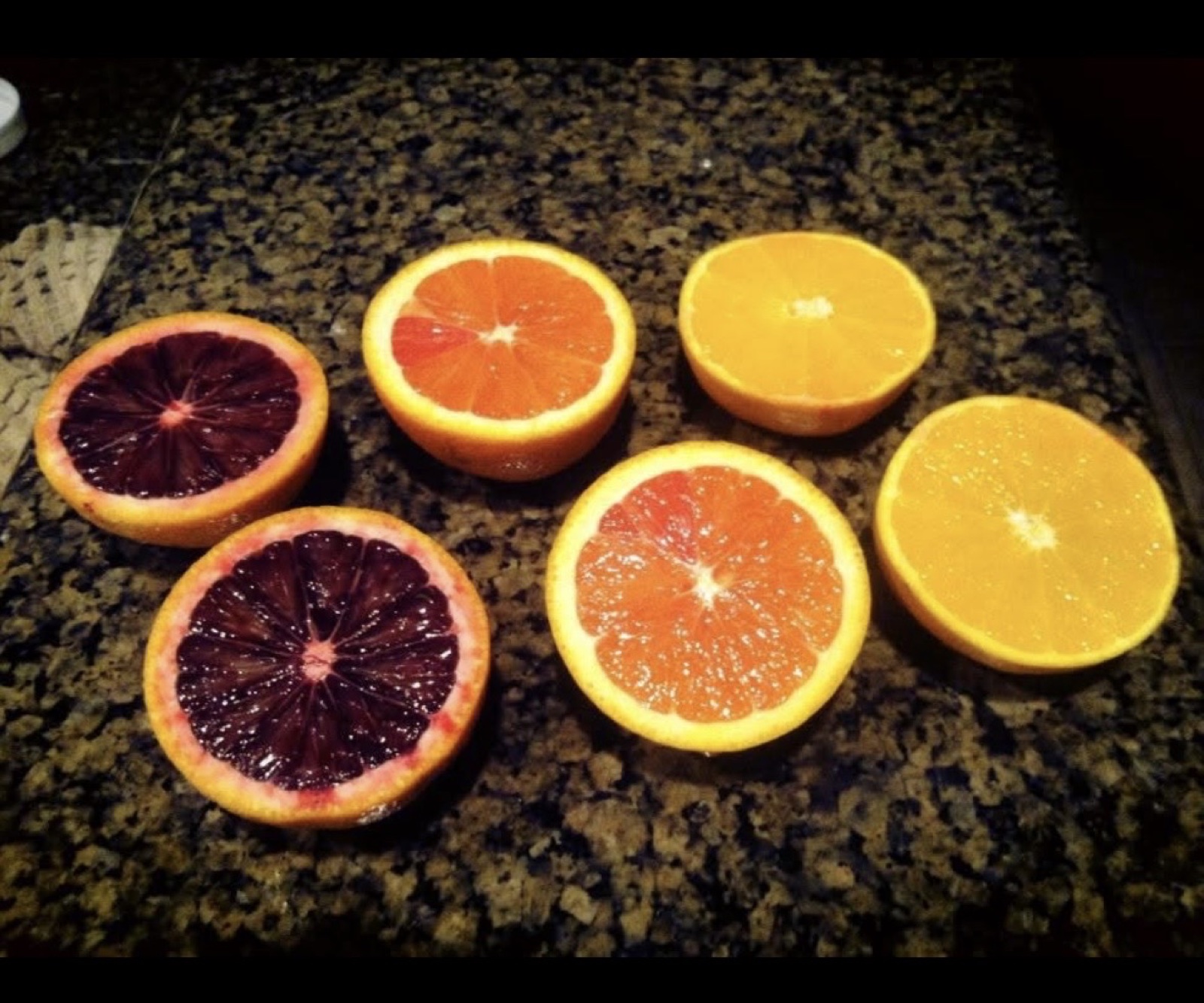 Several colorful citrus varieties cut open to show their different flesh